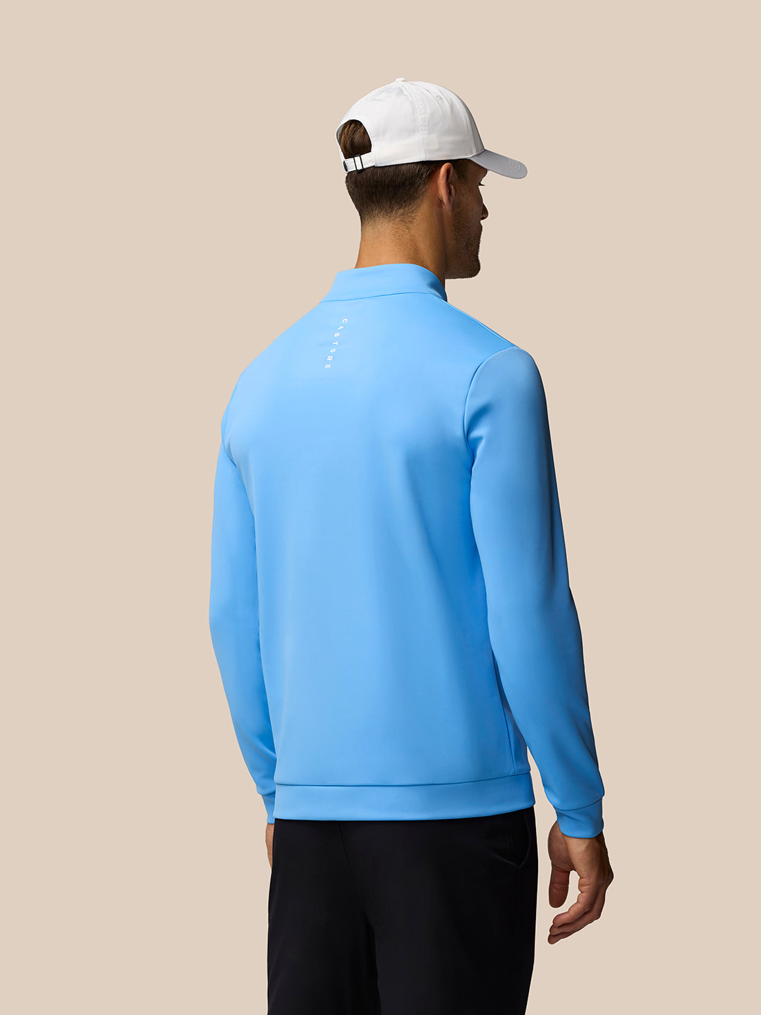 Back view of a man wearing a cool blue Golf Club Classic 1/4 Zip Top with a white cap