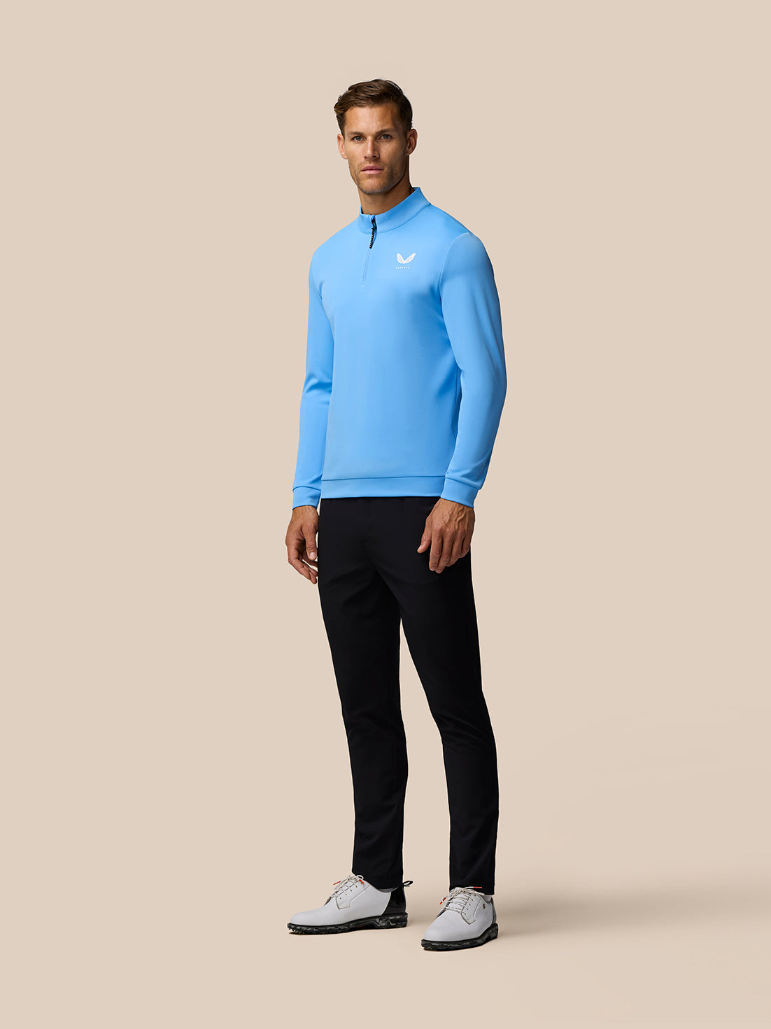 Front view of a man wearing a light blue Castore Golf Club Classic 1/4 Zip Top with a zip collar