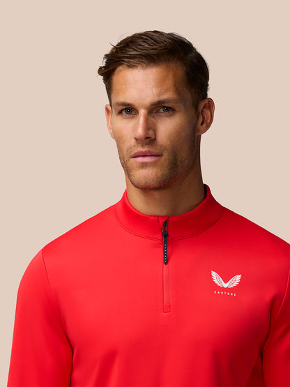 Close up of male model wearing poppy red Golf Club Classic 1/4 Zip Top showing left chest logo