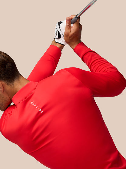 Golfer wearing a red Castore Golf Club Classic 1/4 Zip Top mid swing gripping a golf club