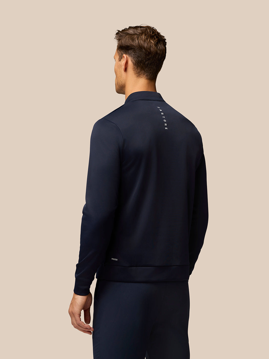 Back view of a man in a midnight navy golf quarter zip top with Castore branding along the upper back