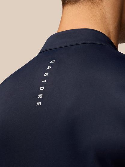 Back view of a man in a navy golf top with vertical Castore branding along the back