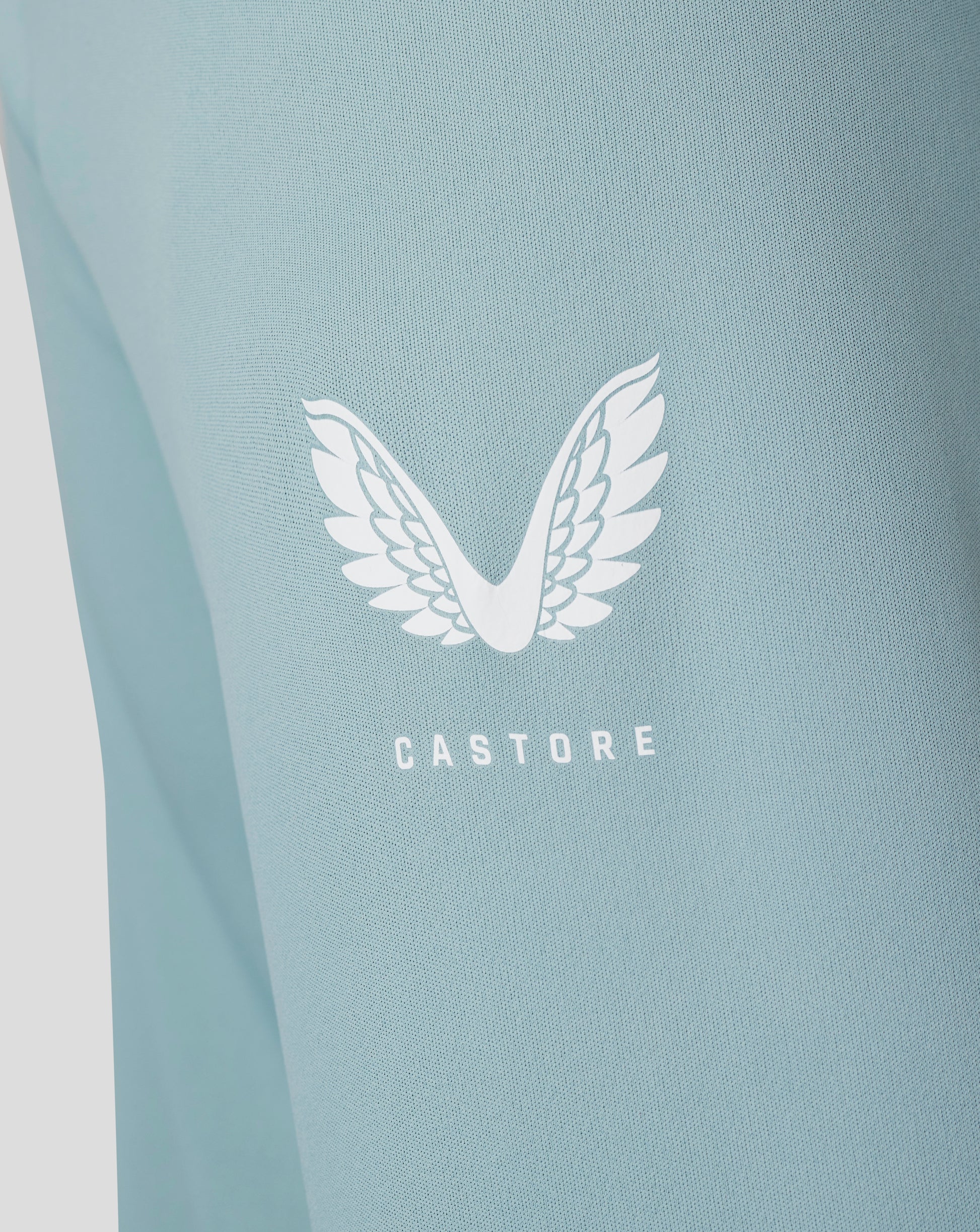 Close-up of stone blue fabric from the Classic 1/4 Zip showing a white Castore wing logo.