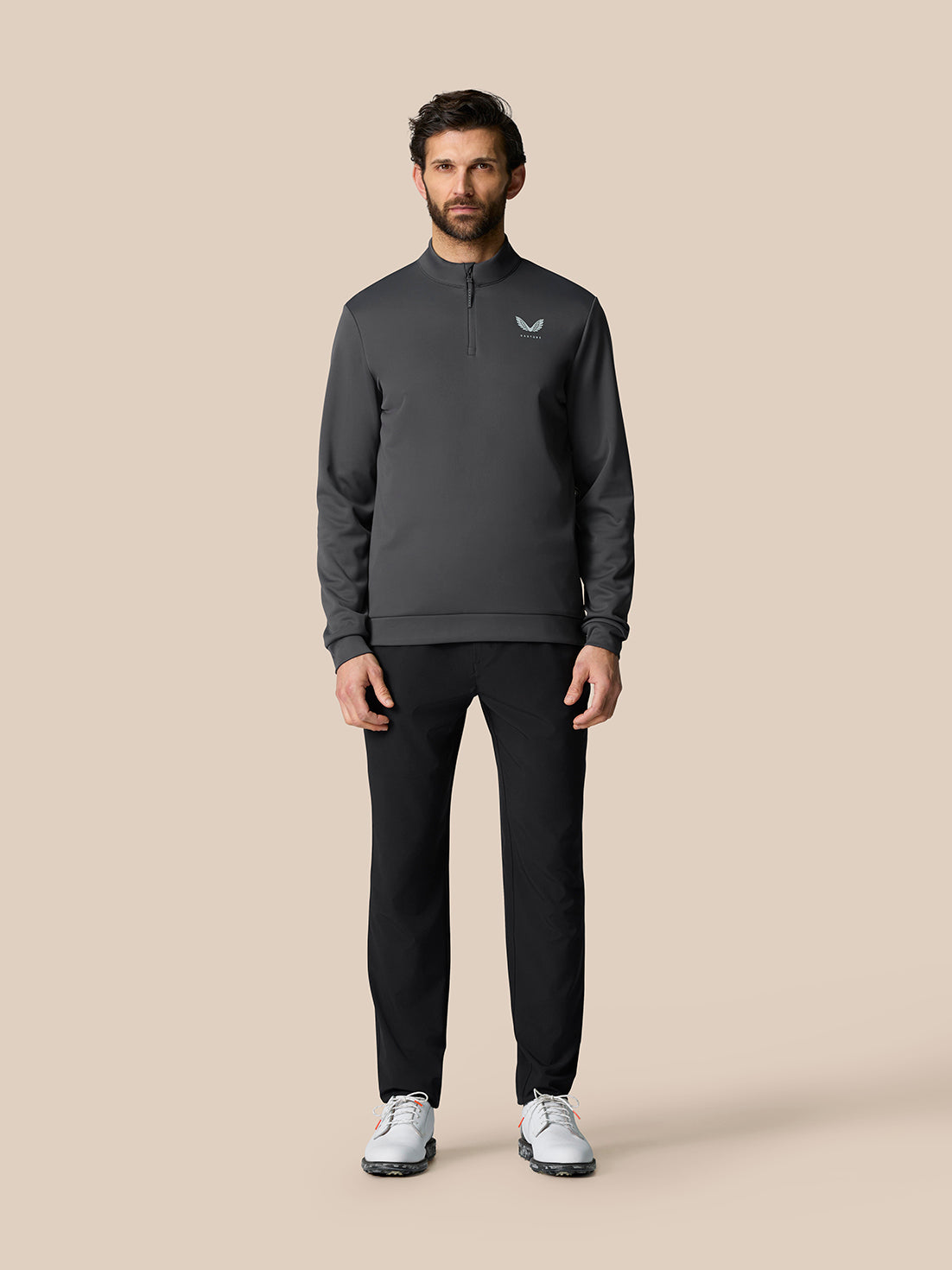Full-length view of a man wearing the gunmetal Golf Club Classic 1/4 Zip Top with black pants and white sneakers.