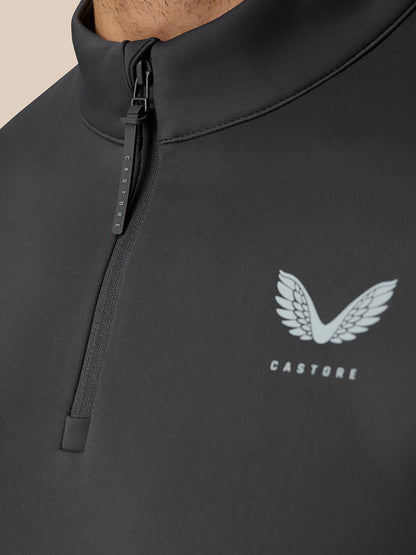 Detail of the zipper with branded pull and Castore logo on the chest of a dark golf top.