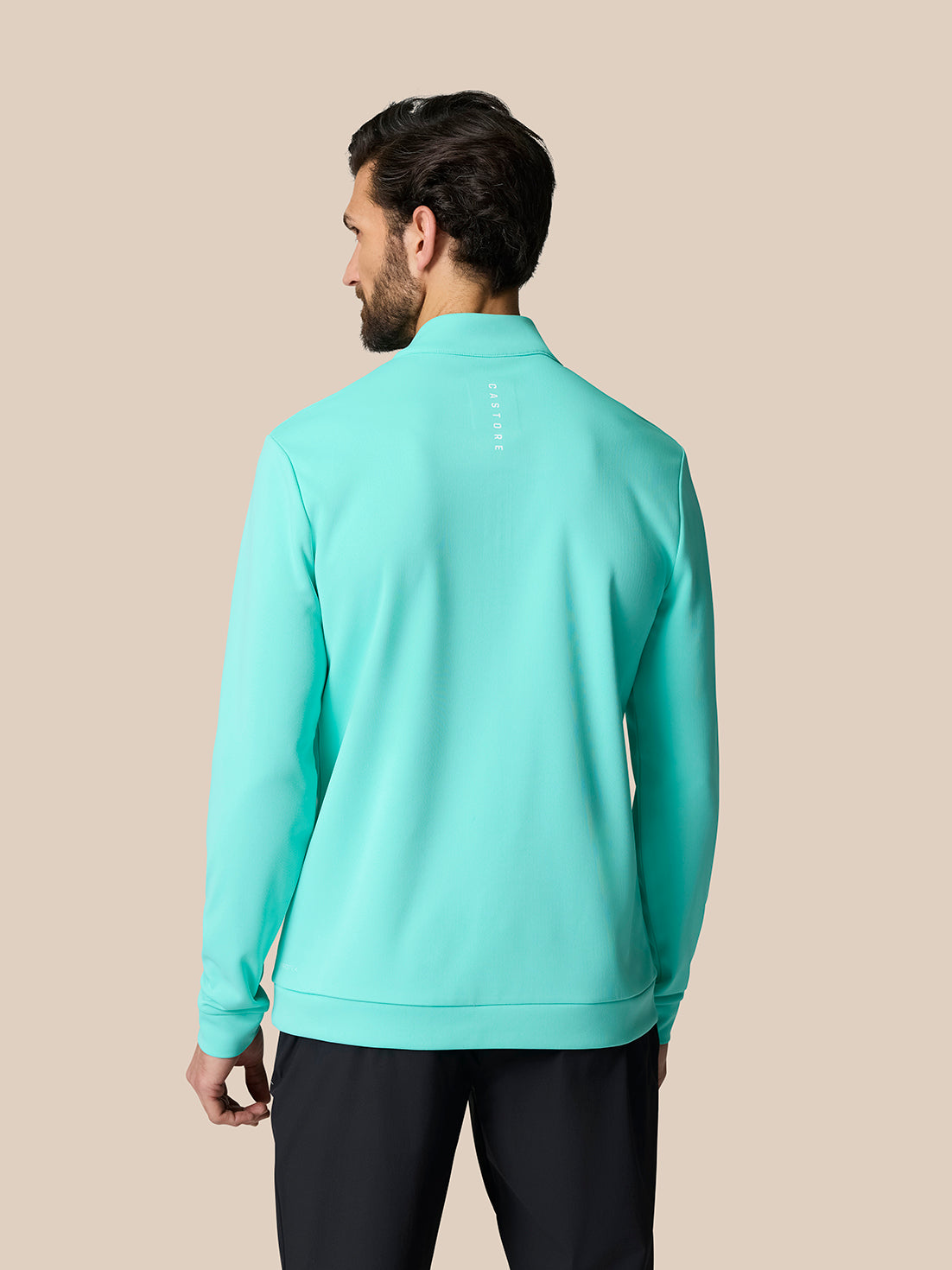 Back view of male model in light aqua Golf Club Classic 1/4 Zip Top with vertical Castore branding on upper back