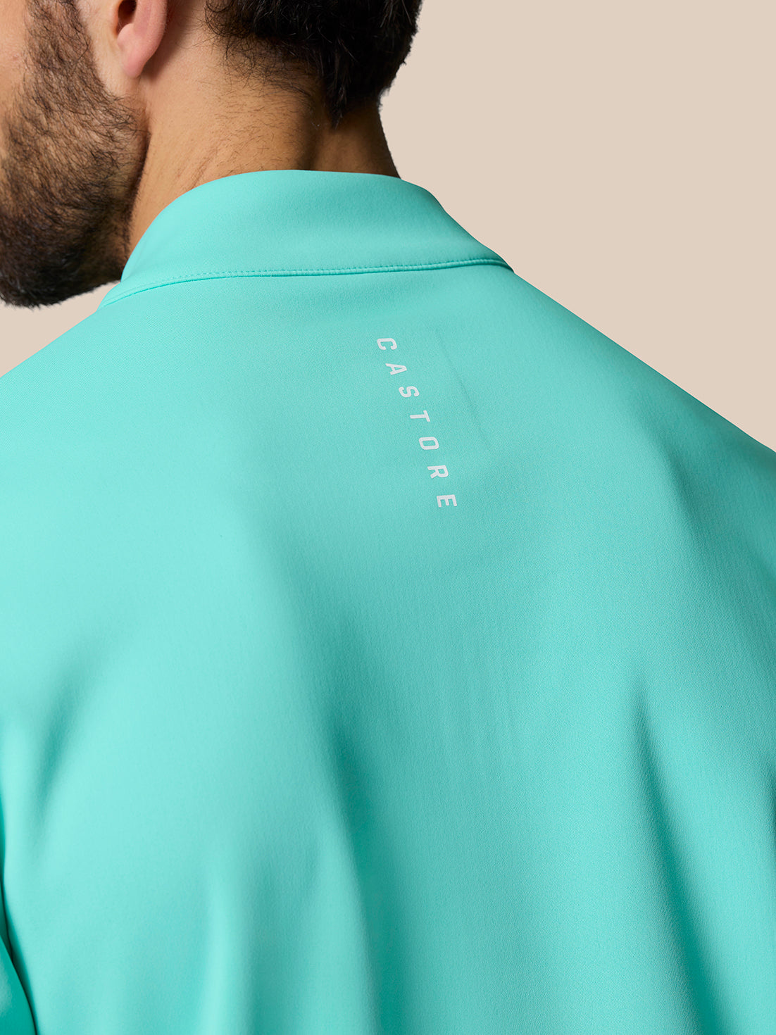 Back view of light aqua Golf Club Classic top with vertical CASTORE branding along the upper back.