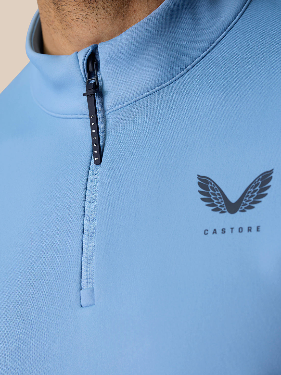 Close-up of sky blue Golf Club Classic 1/4 Zip top showing front zipper and Castore branding on chest