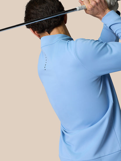 Back view of a golfer in sky blue golf top holding a club behind the head with Castore branding along the back.