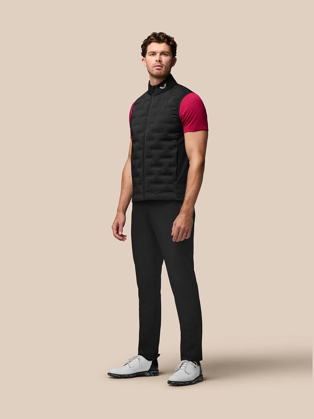 Full-body shot of a man modeling the black Golf Pinnacle Gilet over a magenta T-shirt