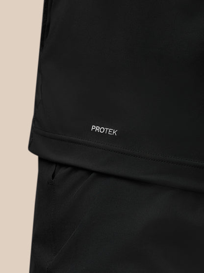 Close-up of the black Pinnacle Gilet fabric with Protek branding near the hem and the front zipper
