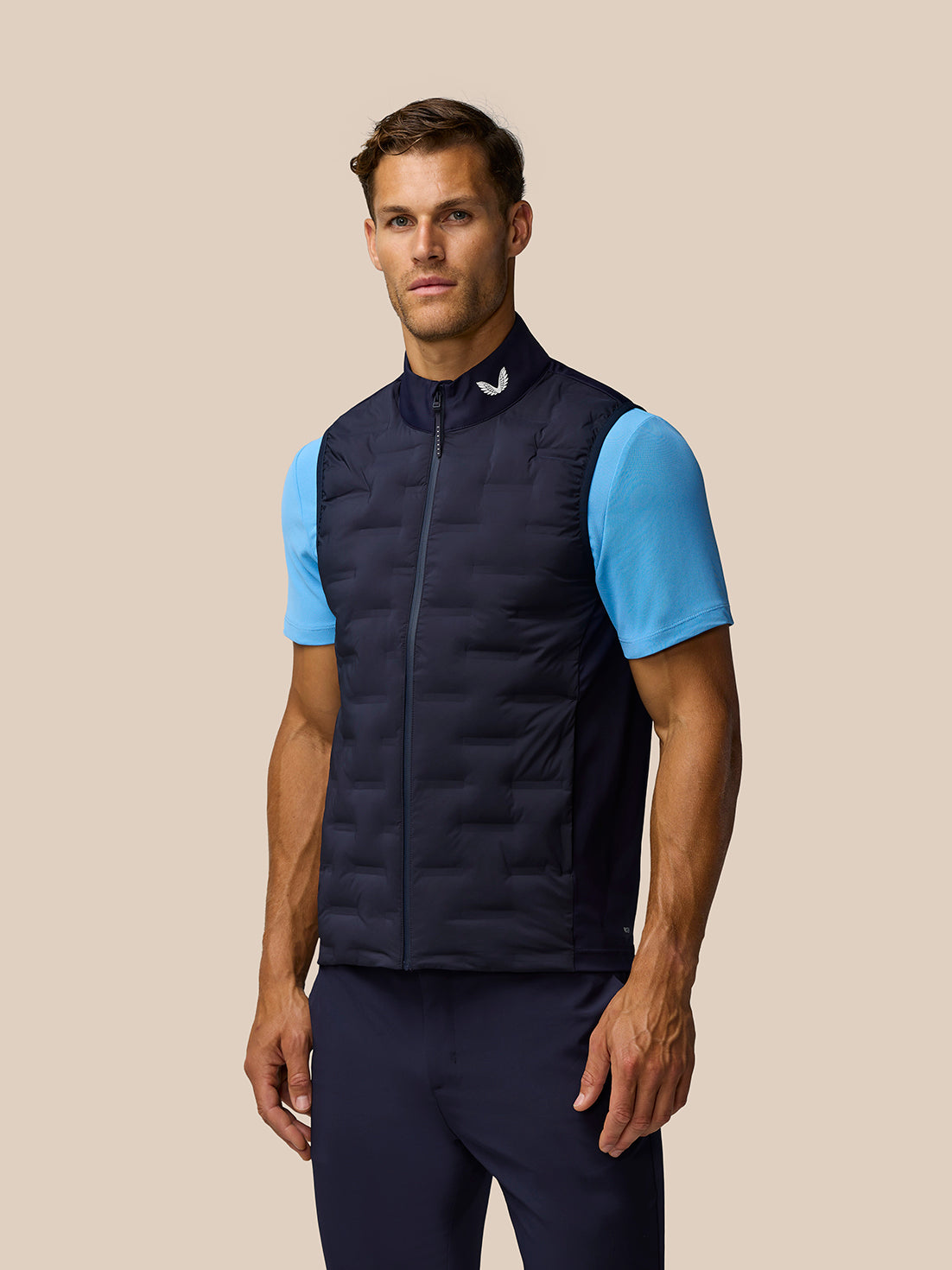 Male model wearing navy Pinnacle Gilet with front zip and high collar over a light blue tee.