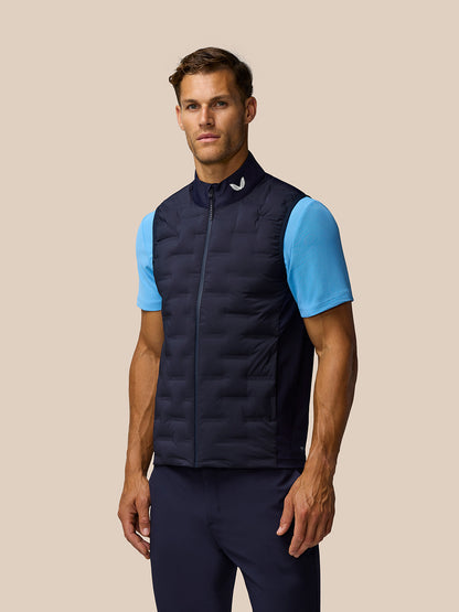 Male model wearing navy Pinnacle Gilet with front zip and high collar over a light blue tee.