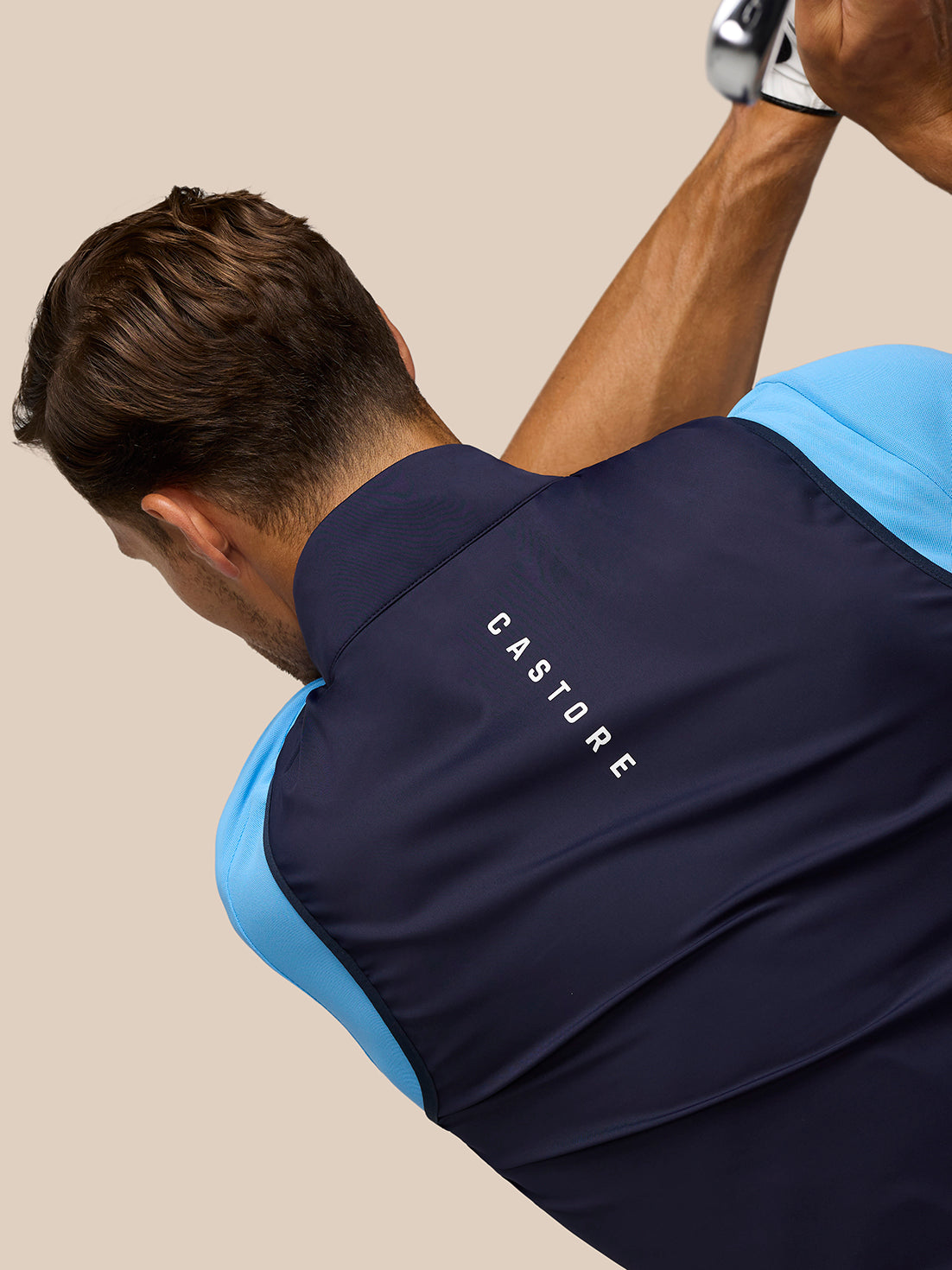 Back view of navy Pinnacle Gilet with light blue sleeves and CASTORE branding along the upper back.