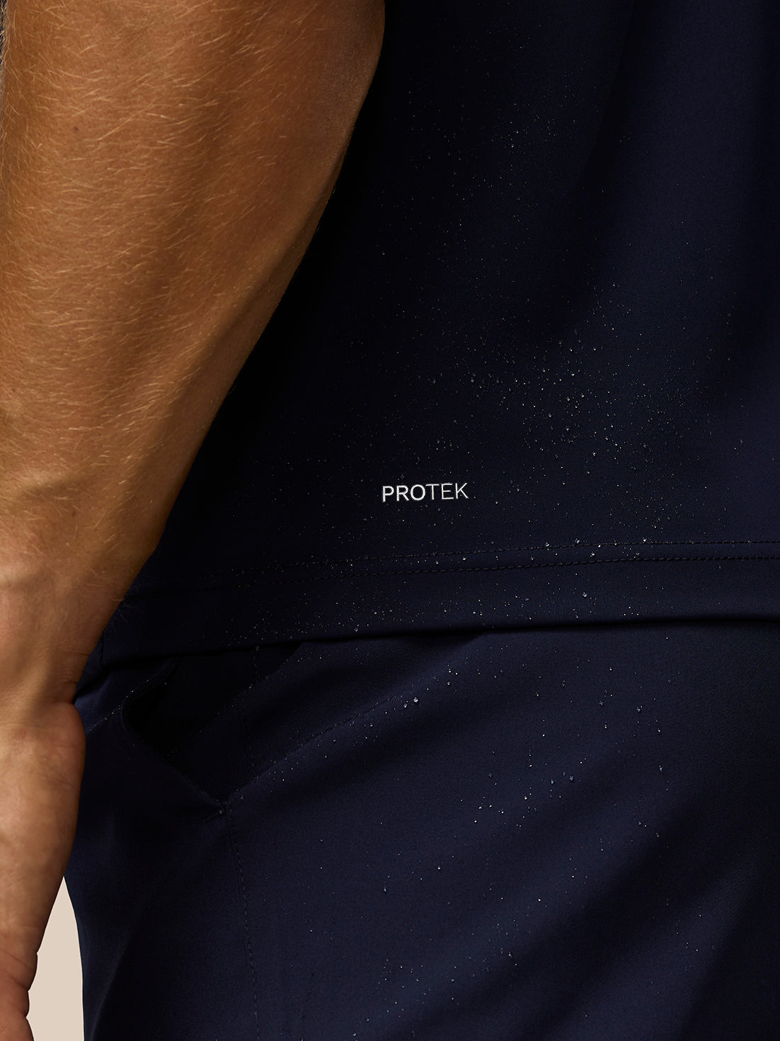 Close-up of navy fabric showing PROTEK label and water resistant texture.