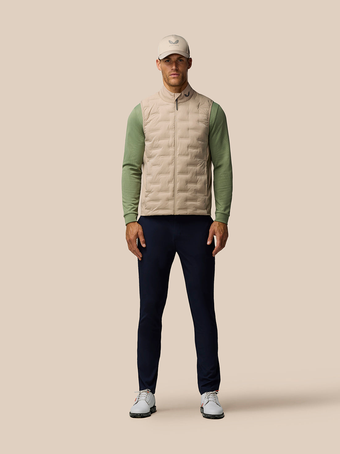 Front view of a male model wearing Mushroom Pinnacle Lightweight Hybrid Gilet with beige torso and green sleeves.