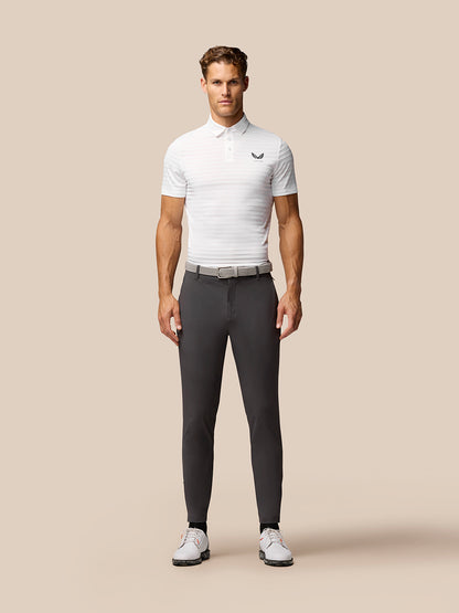Model wearing charcoal golf joggers with a white polo shirt and belt, front view