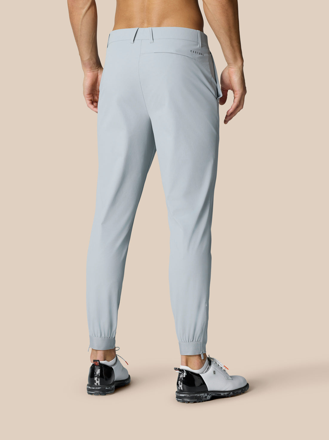 Back view of a man wearing light grey Golf Pinnacle Trousers with Castore branding on the right thigh