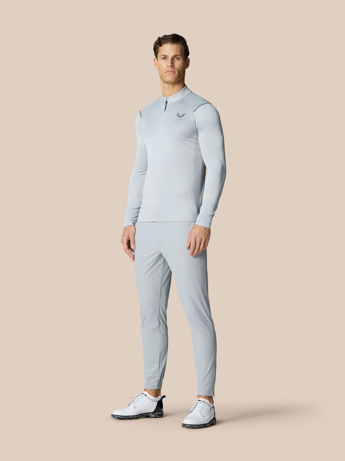 Close up of a golfer in mid grey Pinnacle trousers with Castore branding, gripping a golf club.