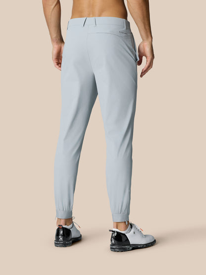 Close-up of mid grey Golf Pinnacle Trousers showing right thigh Castore logo and zippered ankle cuffs.