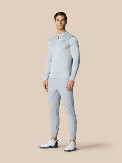 Male model wearing Golf Pinnacle Trousers 32 inch leg in mid grey against a beige backdrop.