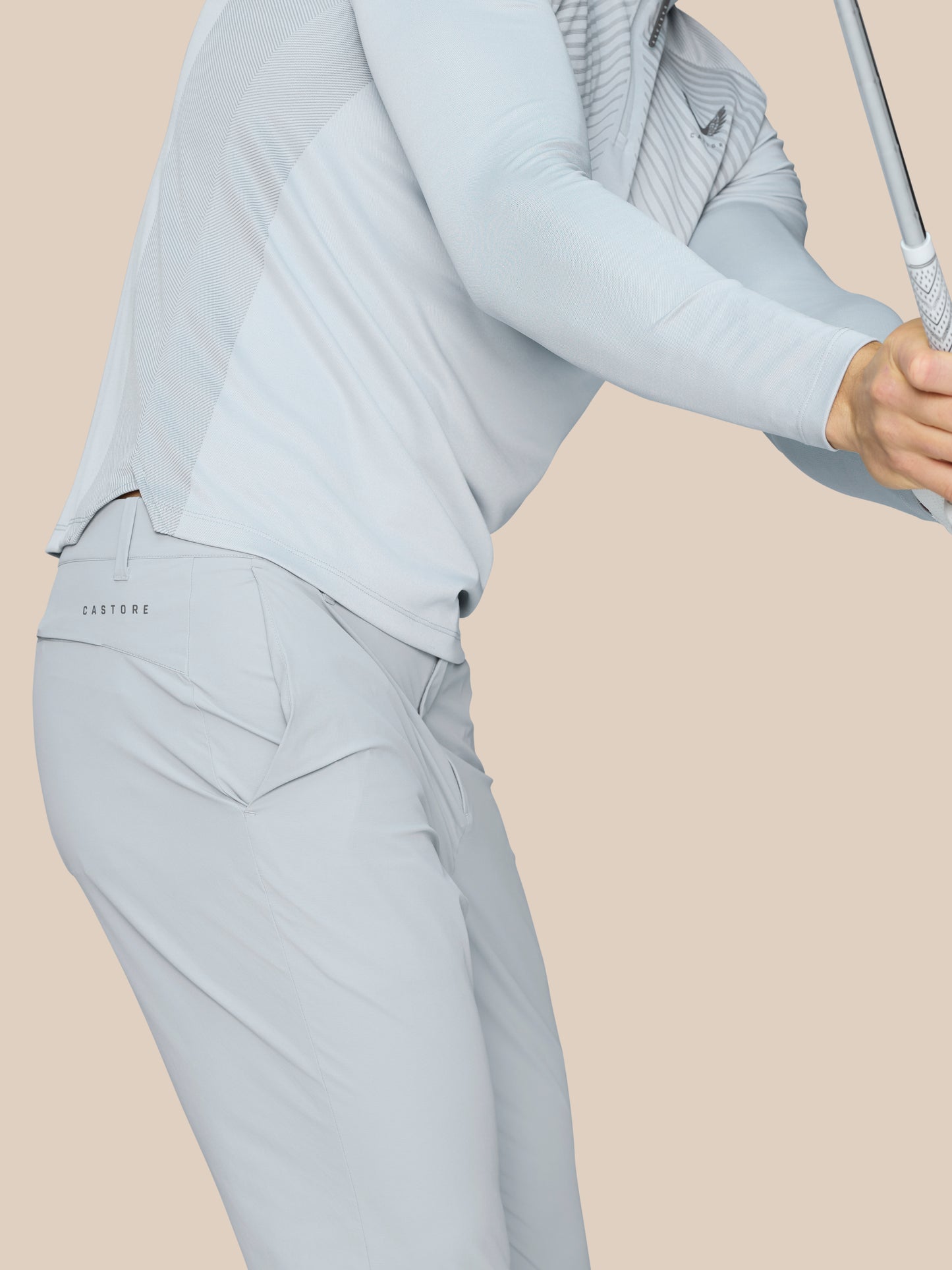 Close-up of light grey Golf Pinnacle Trousers showing a vertical ankle zipper and Castore branding on the hip