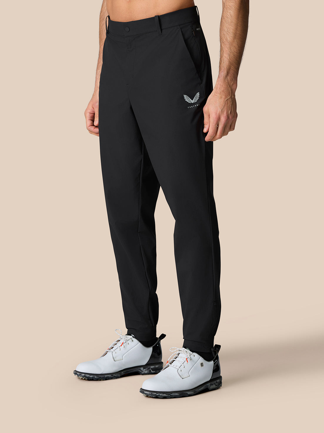 Front view of a model wearing black Golf Pinnacle Trousers 32 inch leg with white golf shoes.