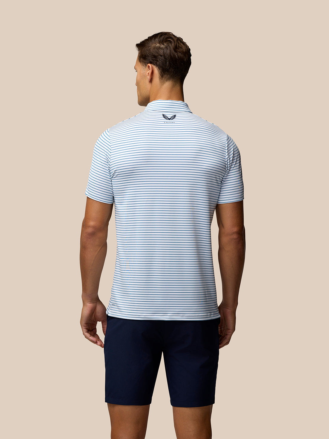 Back view of a man in a white and blue striped Club Golf Stripe Polo highlighting the stripe pattern and back branding