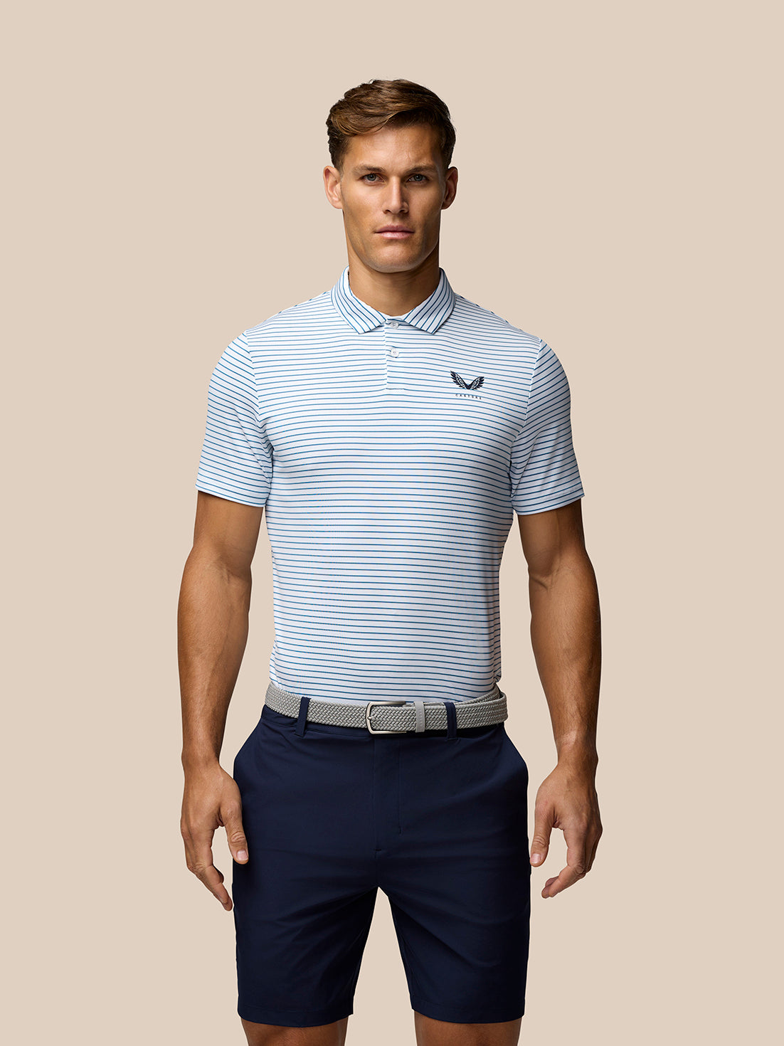 Male model wearing Club Golf Stripe Polo in white with blue stripes and Castore logo on the chest.
