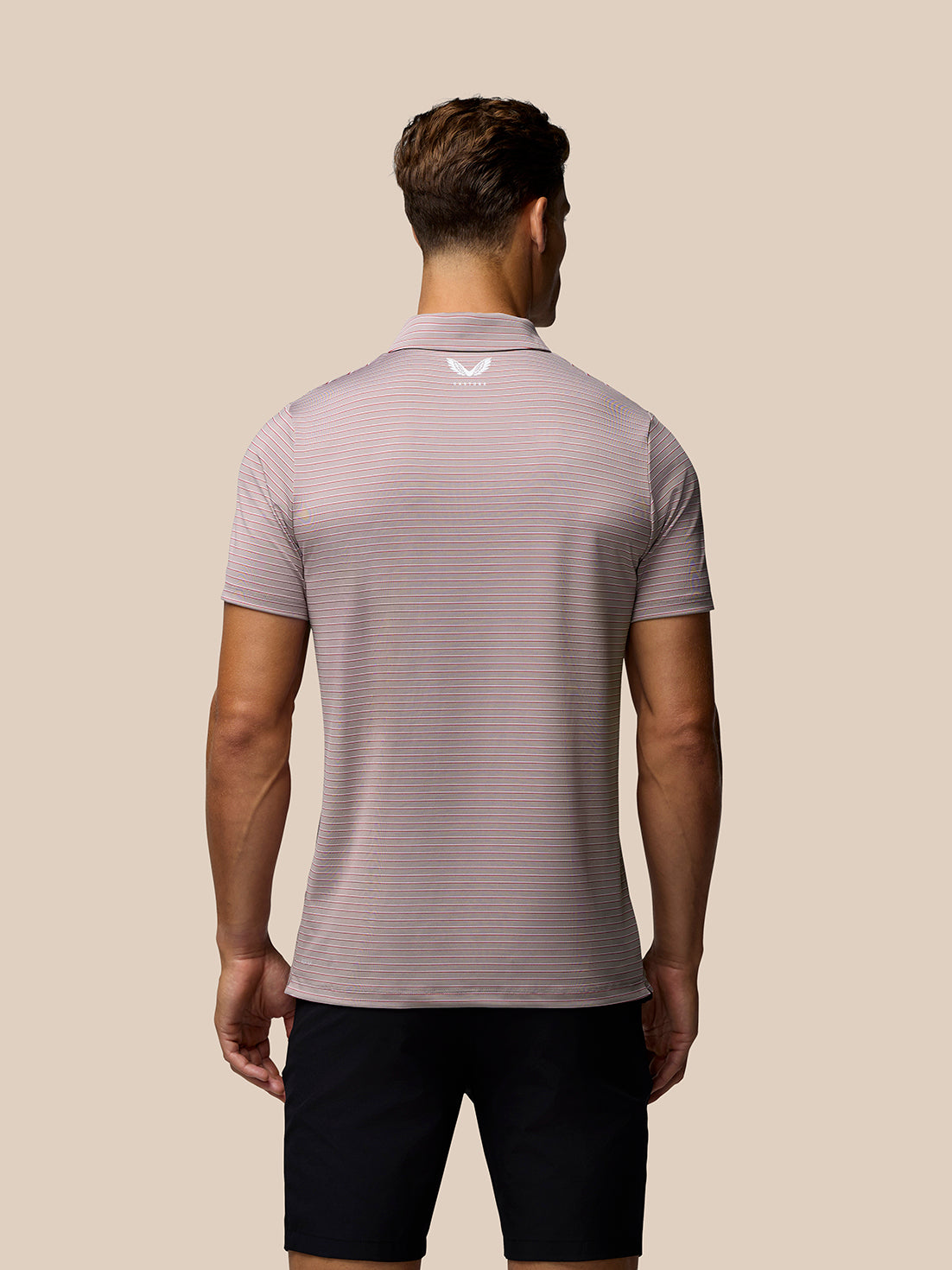 Model wearing light pink striped golf polo with short sleeves and white Castore logo on left chest