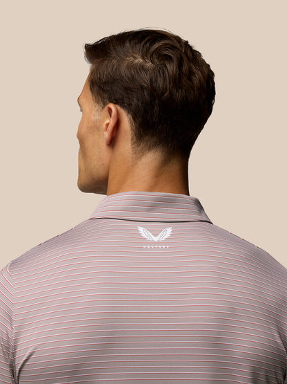 Back view of male model in pink yarn-dye stripe golf polo showing Castore logo on upper back and Aertek branding at lower left back.