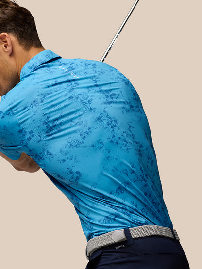 Male golfer wearing a blue Geo Print Club Polo with a golf club arcing over his shoulder.