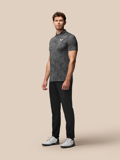 Male model wearing Club Golf Polo in charcoal with all over geo print and black pants