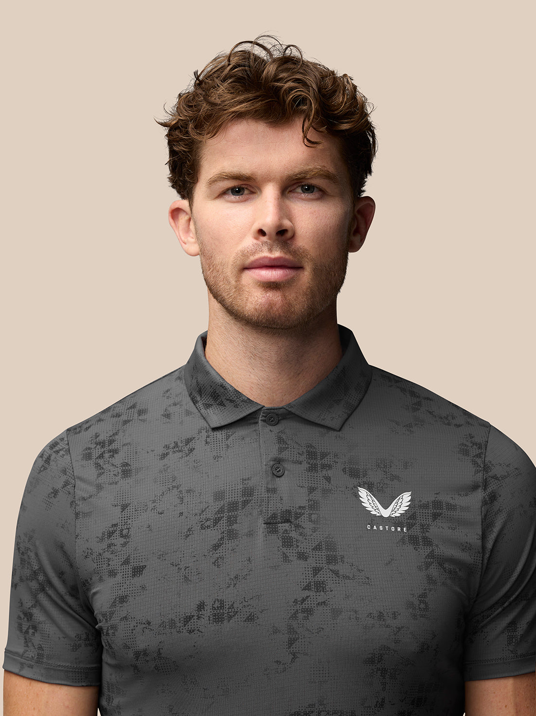 Detail shot of back of charcoal geo print polo showing vertical Castore branding