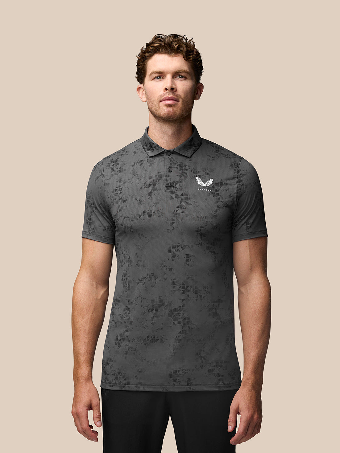 Man wearing charcoal geo print polo with Castore branding on the chest