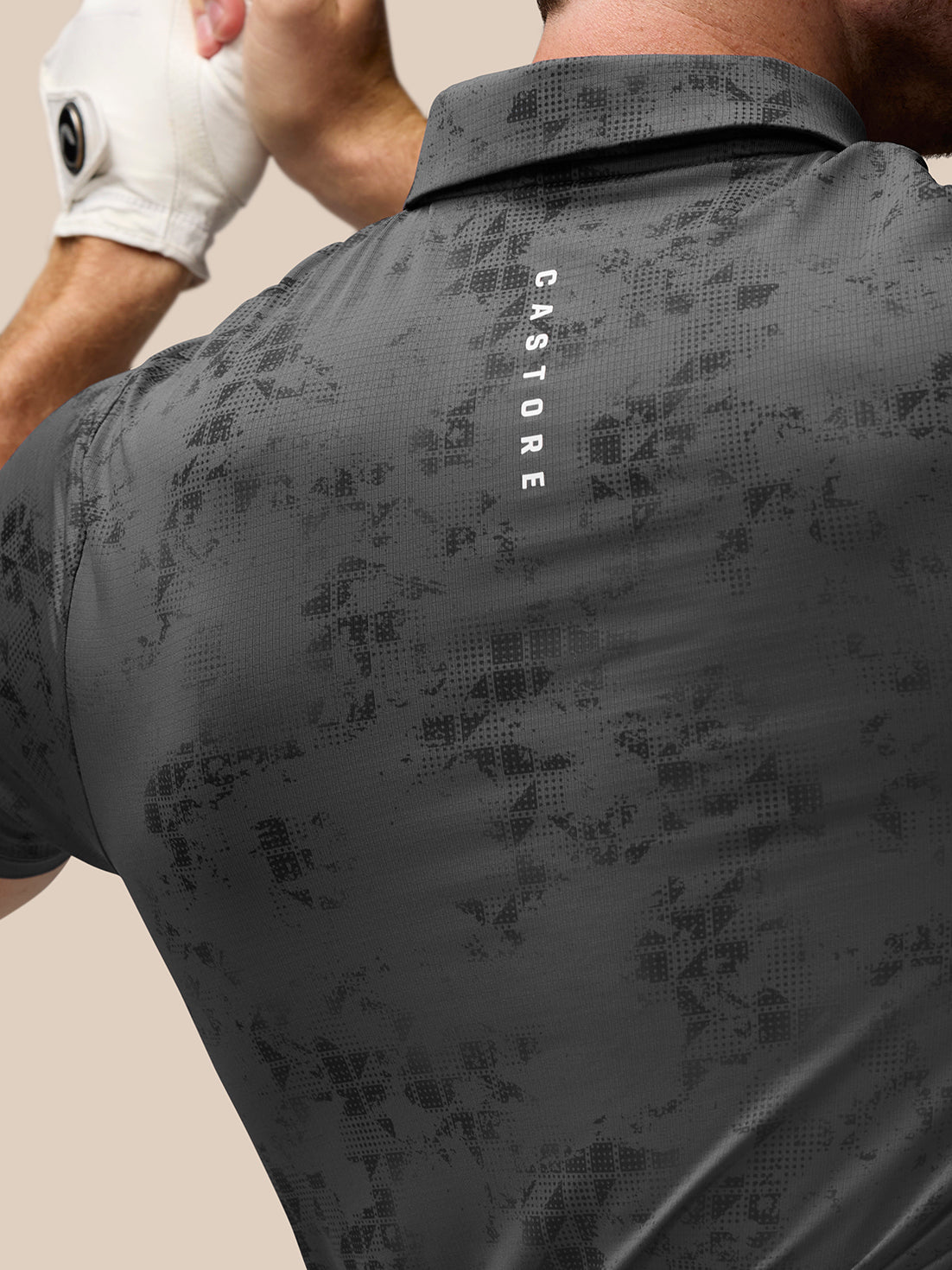 Rear view of a male model in charcoal geo print golf polo highlighting the all over pattern