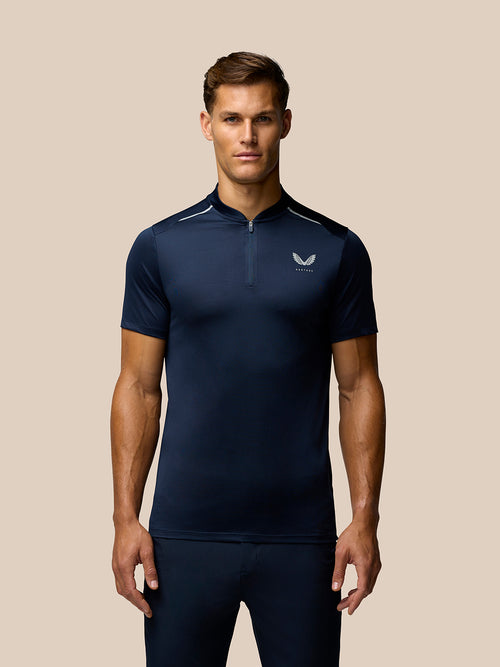 Male model wearing navy Pinnacle Varsity Polo with quarter zip and Castore logo on left chest