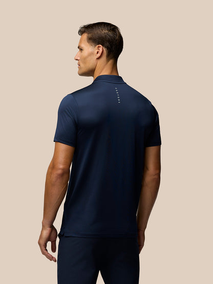 Back view of male model in navy Pinnacle Varsity Polo showing Castore branding on upper back