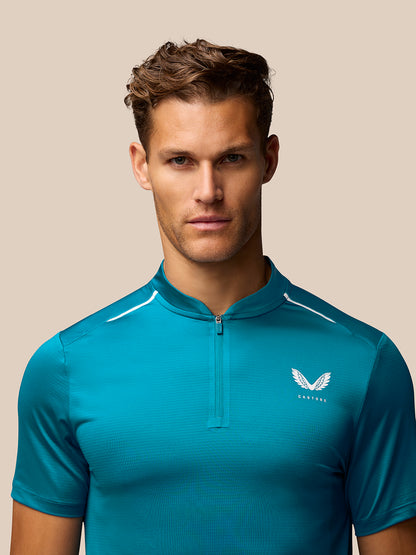 Male model wearing teal Pinnacle Golf Varsity Polo with front zip and Castore logo on the chest