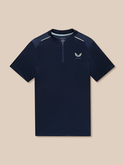 Flat-lay navy Pinnacle Varsity Polo with quarter zip and left chest logo against a beige background.
