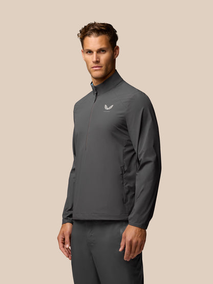 Male model wearing charcoal Golf Half Zip Top with stand collar front zip pockets and Castore logo on chest