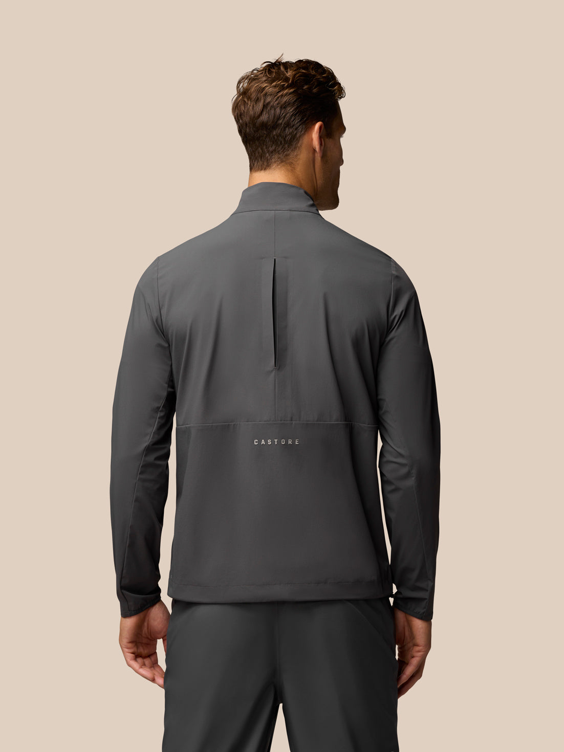 Male model in charcoal Golf Half Zip Top with stand collar and zip pockets; Castore logo on chest
