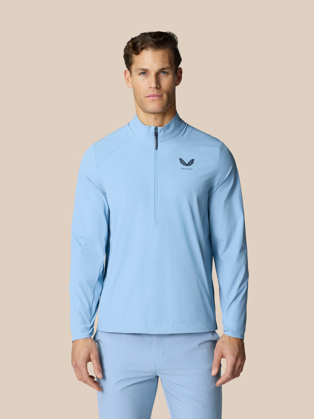 Model wearing sky blue Golf Flex Jacket with half zip at front and Castore logo on chest.