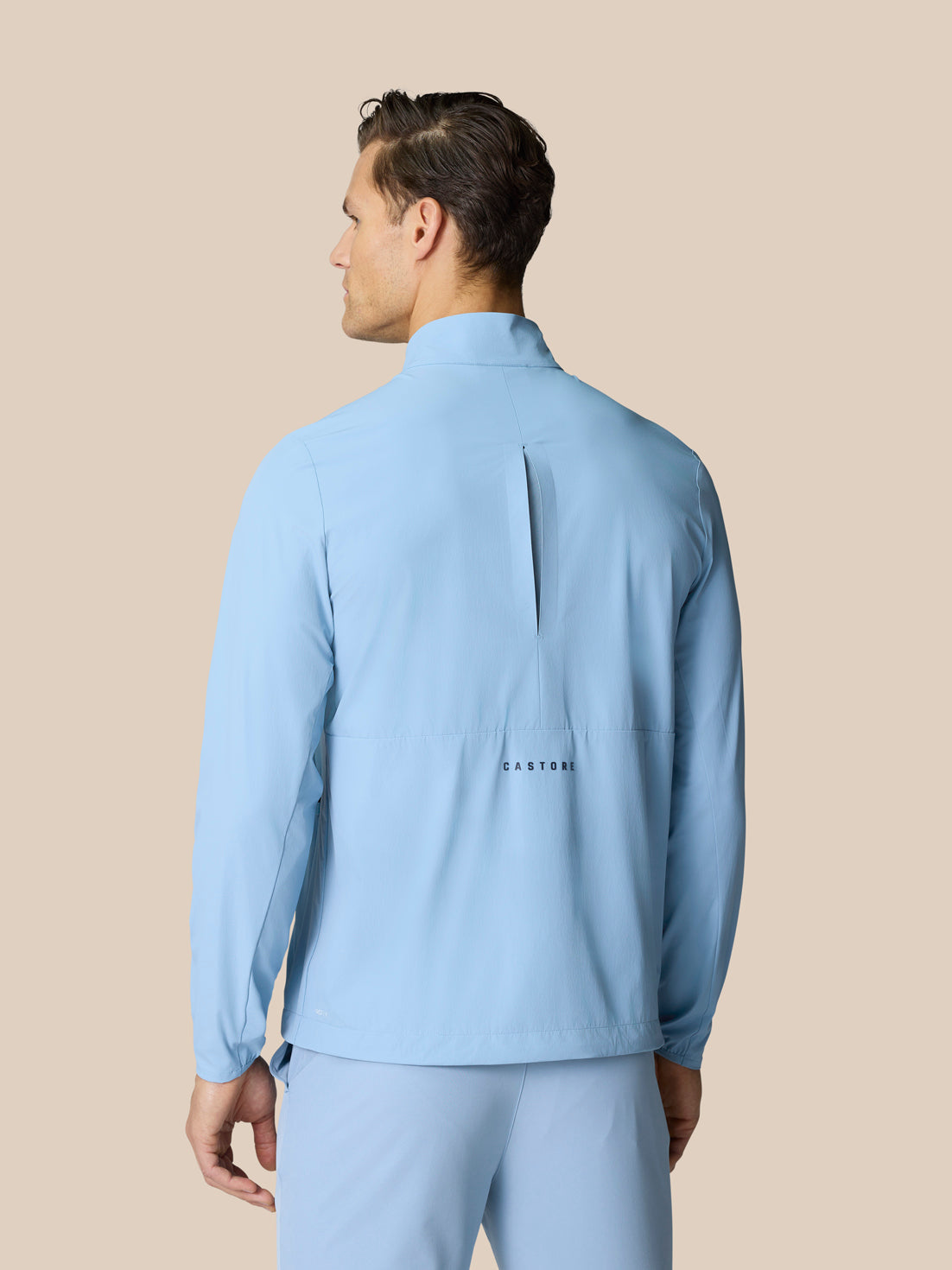 Back view of sky blue Golf Flex Jacket with Castore graphic on lower back.