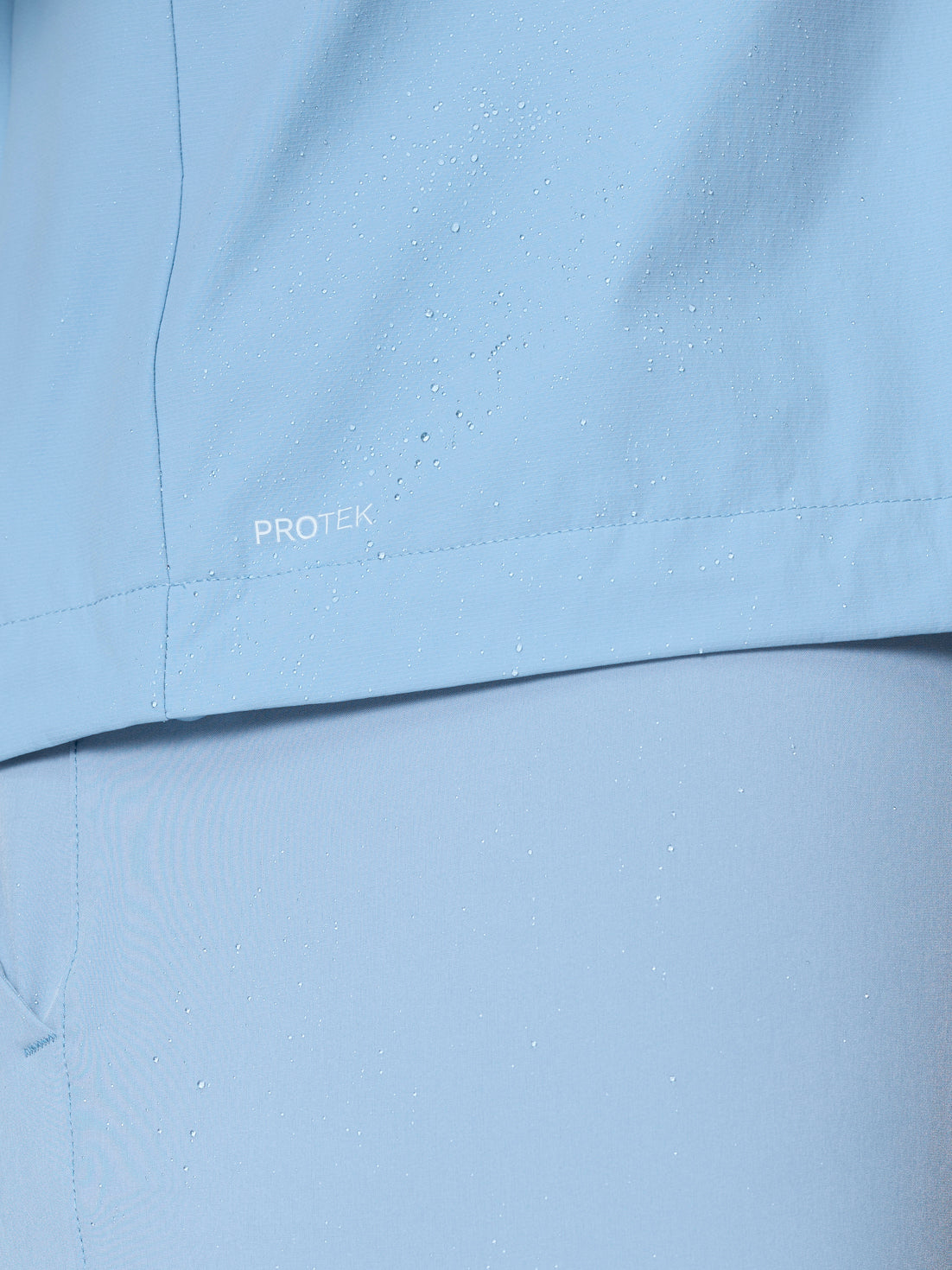 Close up of water droplets on sky blue Flex Jacket fabric highlighting ProTek water resistant finish