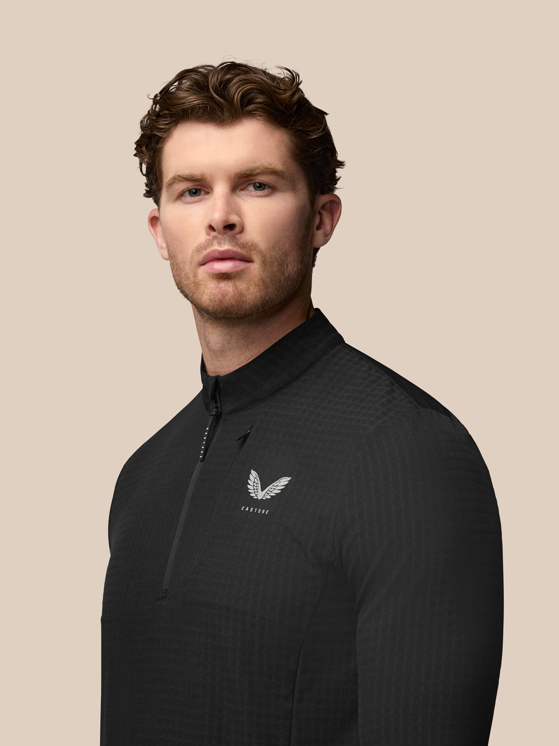Three quarter rear view of black golf top showing the Castore wing logo on the left chest and vertical branding on the upper back
