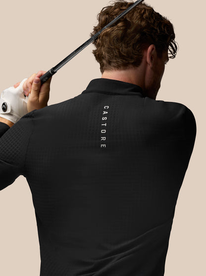 Back view of black golf top on a model with vertical Castore branding along the upper back