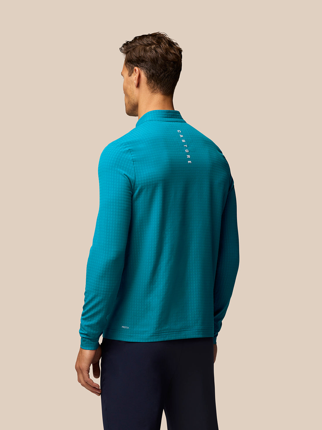 Back view of blue Golf 1/2 Zip Top on a male model with vertical CASTORE branding along the upper back.