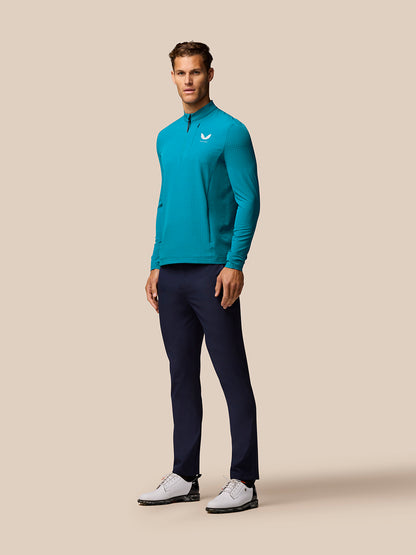 Male model wearing turquoise Golf 1/2 Zip Top with stand collar and half zip, navy pants and white shoes