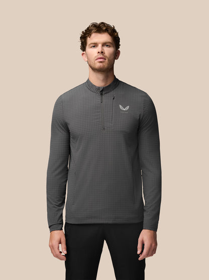 Grey golf 1/2 zip top on a male model with stand collar and chest zip pocket; Castore branding on the chest.